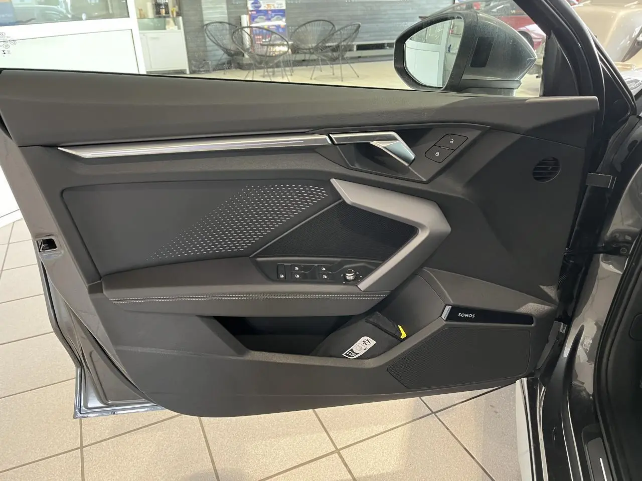 Vue intérieure de la porte avant gauche gris métallisé de l'Audi A3 Sportback 2025 avec finitions S line et haut-parleur Sonos intégré.
