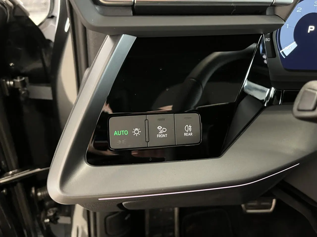 Détail du tableau de bord côté gauche de l'Audi A3 Sportback gris 2025 avec commandes d'éclairage et finition noire brillante.