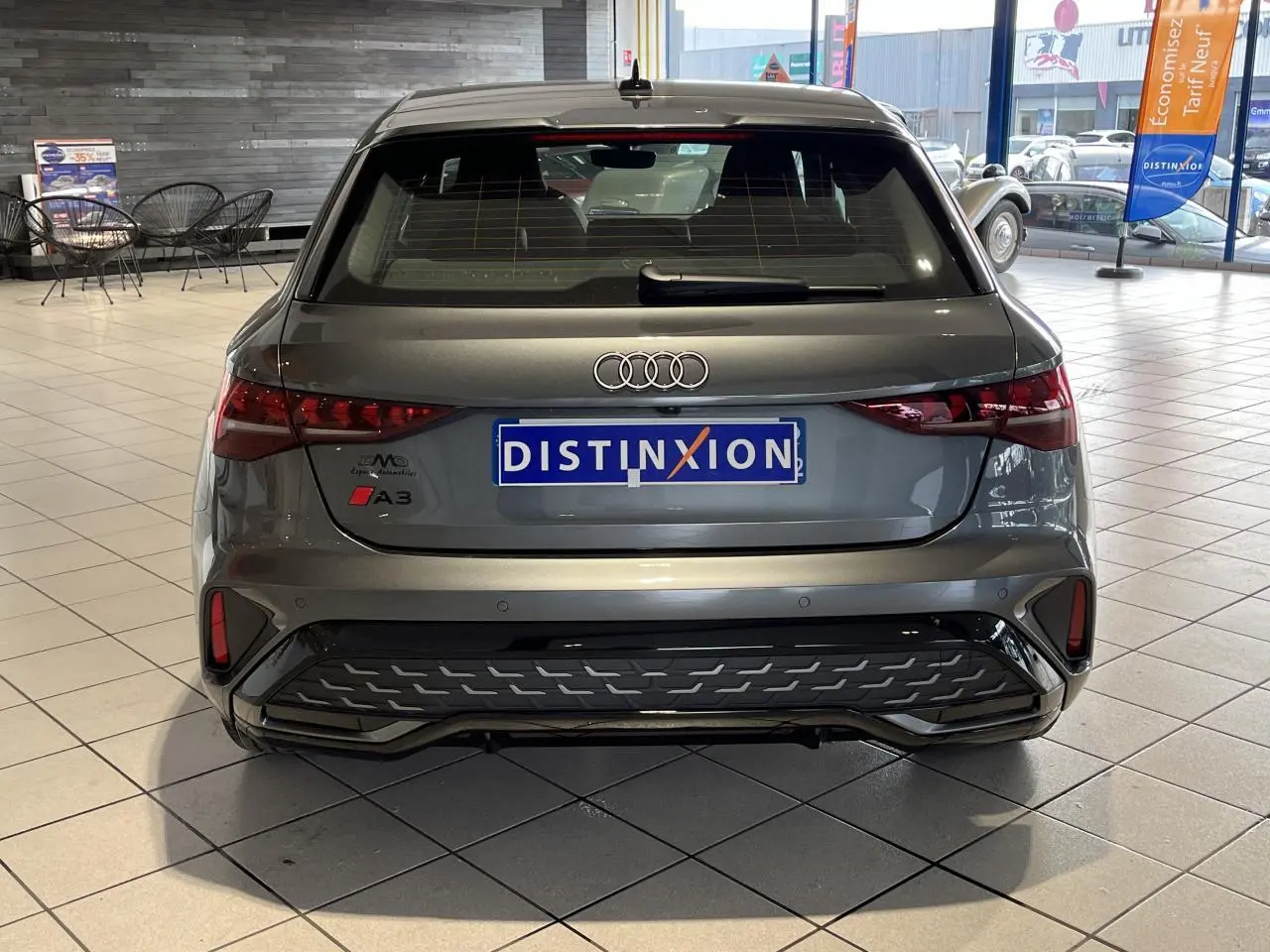 Vue arrière d'une Audi A3 Sportback gris métallisé avec détails S line et feux arrière LED dynamiques en showroom.