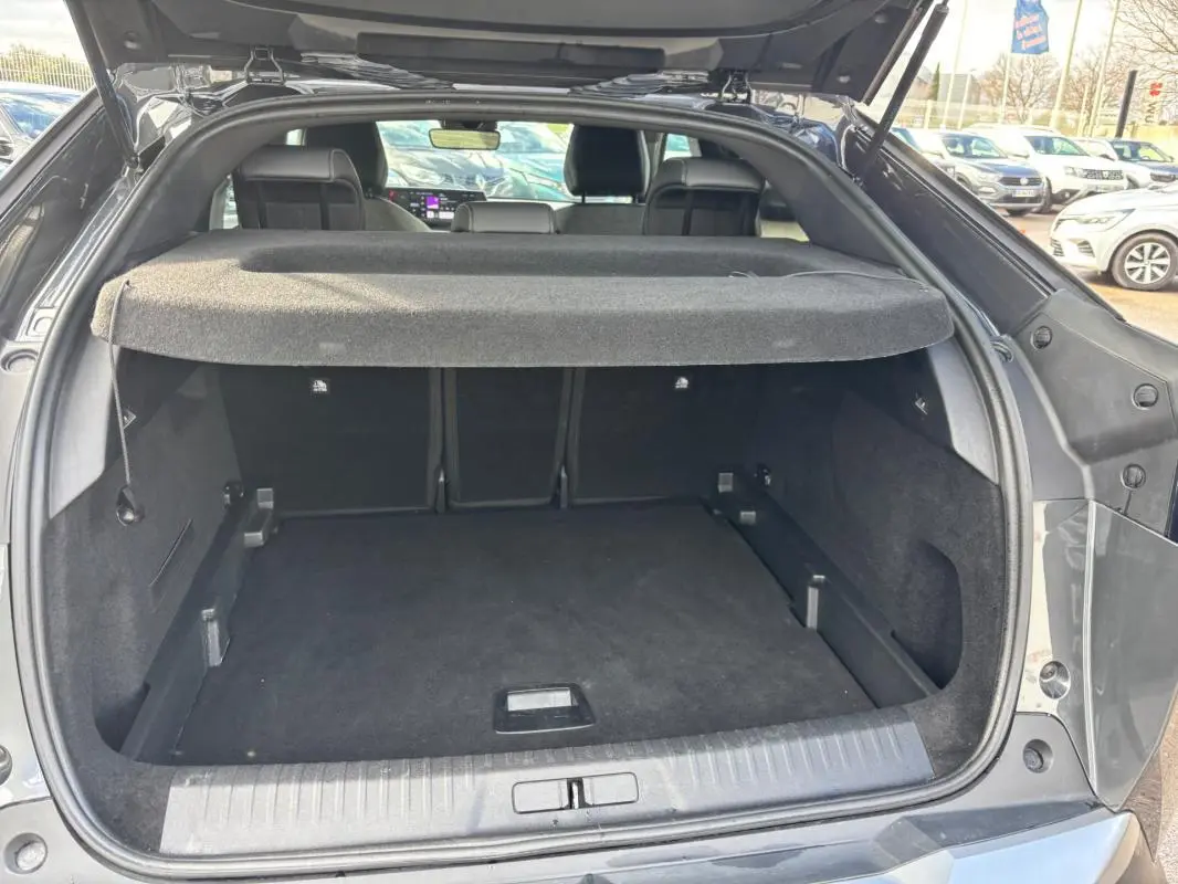 Coffre ouvert du Peugeot 3008 Hybrid gris, vue arrière montrant l’espace de chargement et la plage arrière.