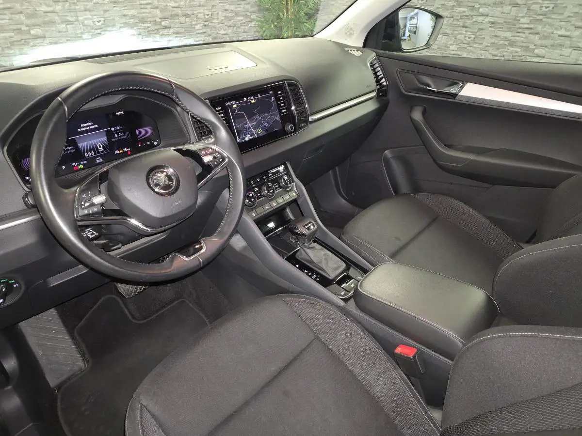 Intérieur avant droit du Skoda Karoq 2024, tableau de bord noir avec écran tactile et volant cuir multifonctions.