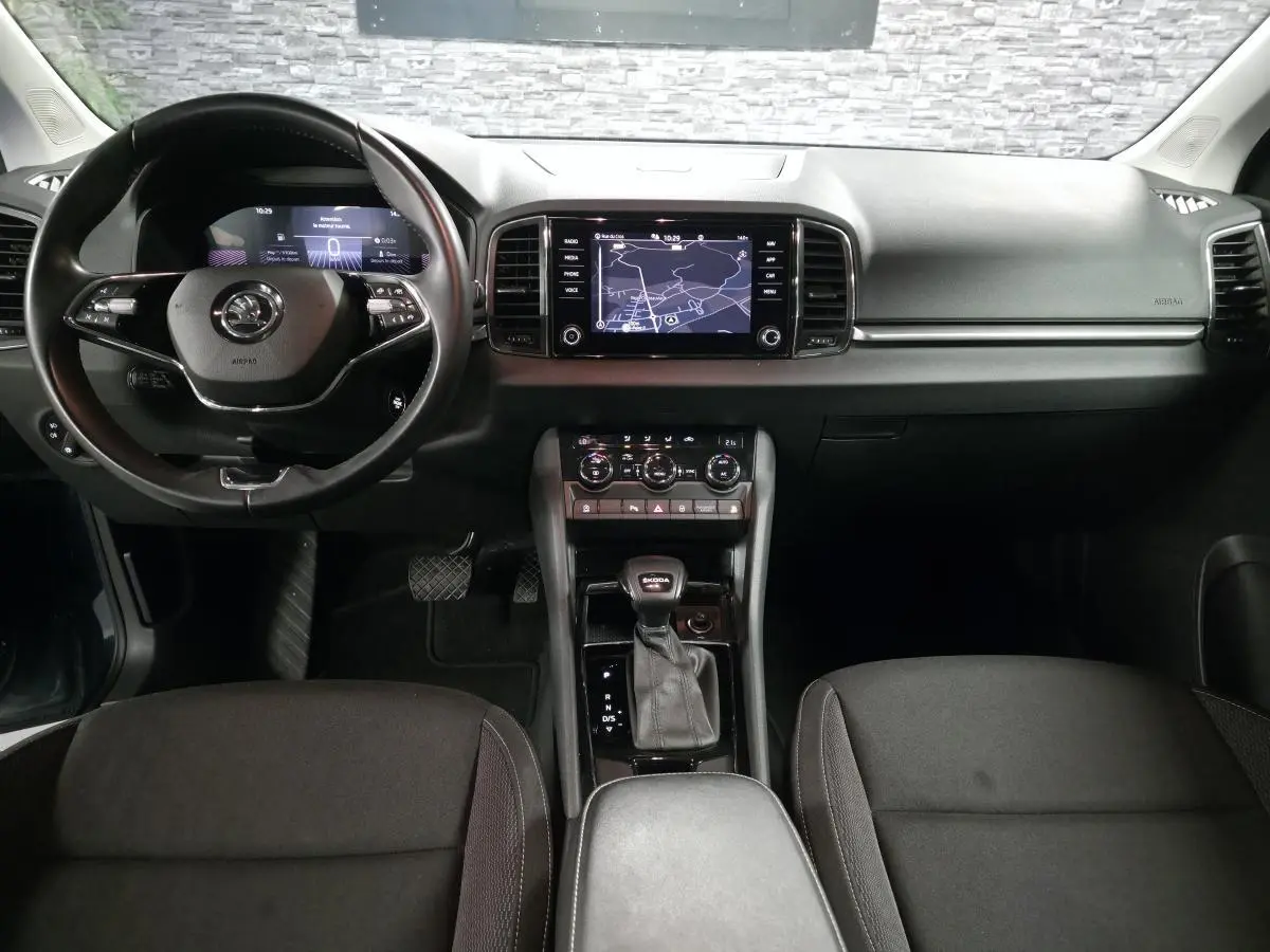 Vue intérieure avant du Skoda Karoq 2024, tableau de bord noir avec écran tactile et volant cuir multifonctions.