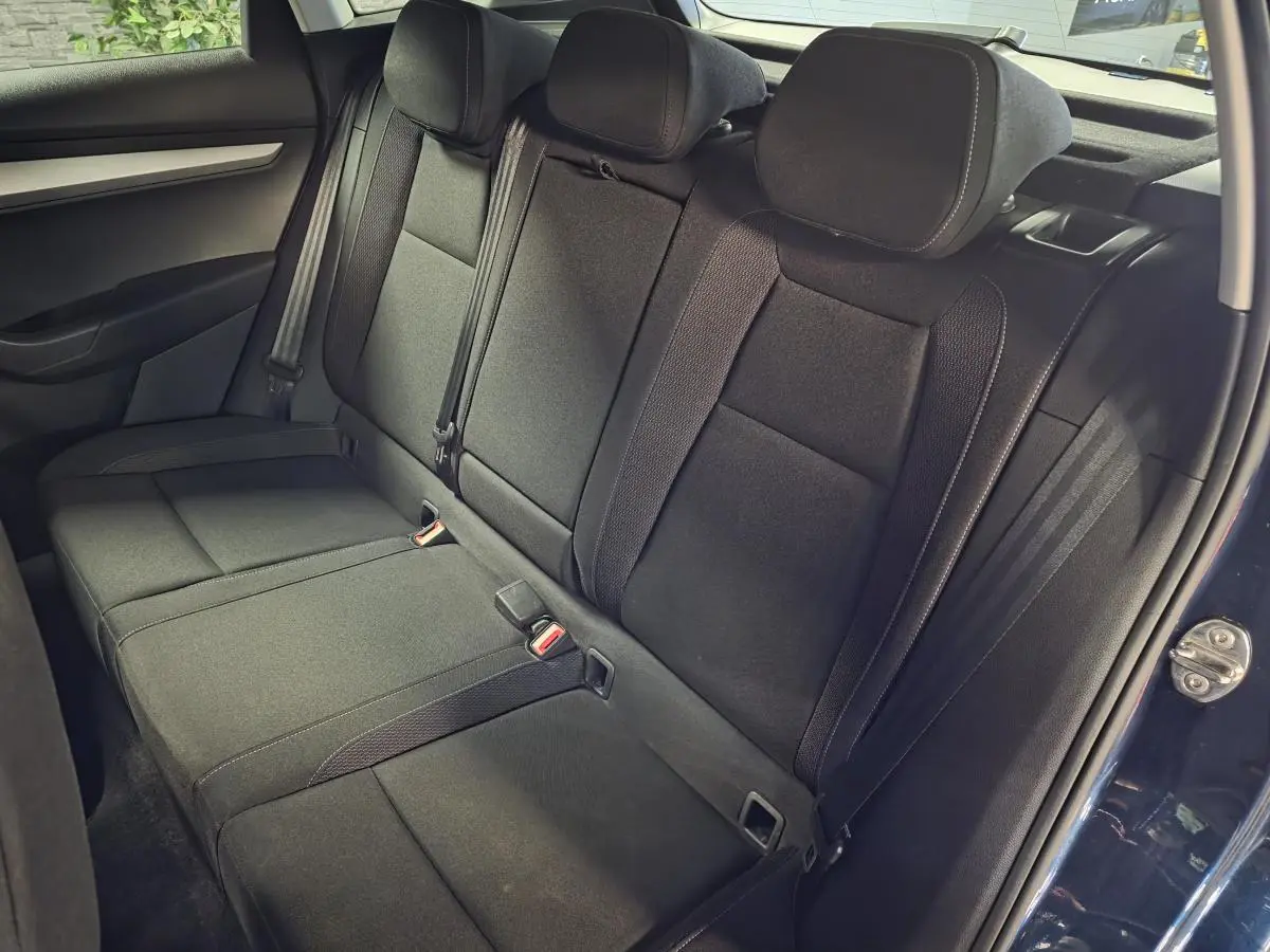 Vue intérieure de la banquette arrière noire du Skoda Karoq bleu, avec trois appuie-tête et ceintures de sécurité visibles.