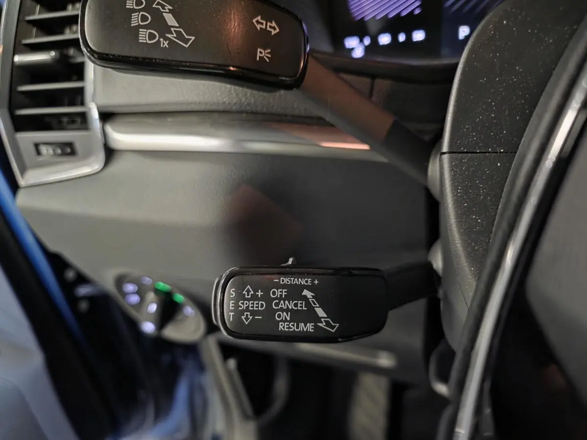 Gros plan sur la commande de régulateur de vitesse à gauche du volant du Skoda Karoq bleu 2024.