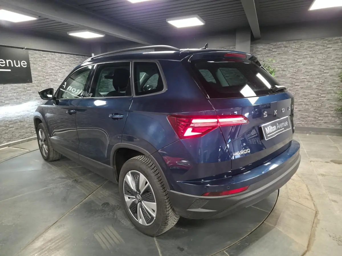 Vue 3/4 arrière droite d’un Skoda Karoq bleu métallisé avec feux arrière LED et jantes alliage 17 pouces.