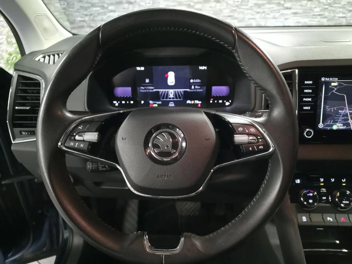 Vue frontale du volant cuir noir du Skoda Karoq 2024 avec tableau de bord digital et écran tactile de navigation.