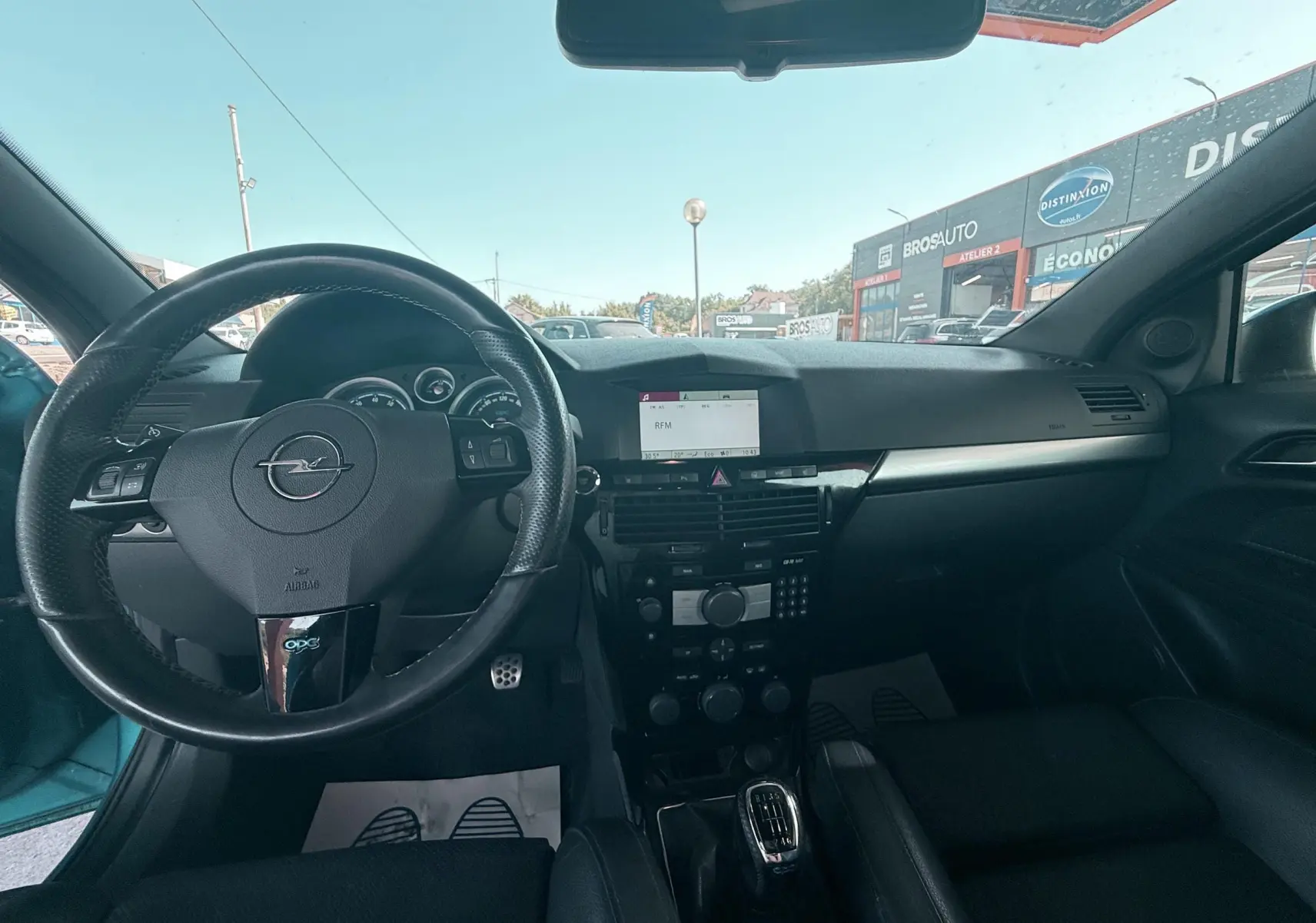 Vue intérieure avant de l’Opel Astra OPC 2008 avec volant cuir noir, tableau de bord et levier de vitesse manuel visibles.