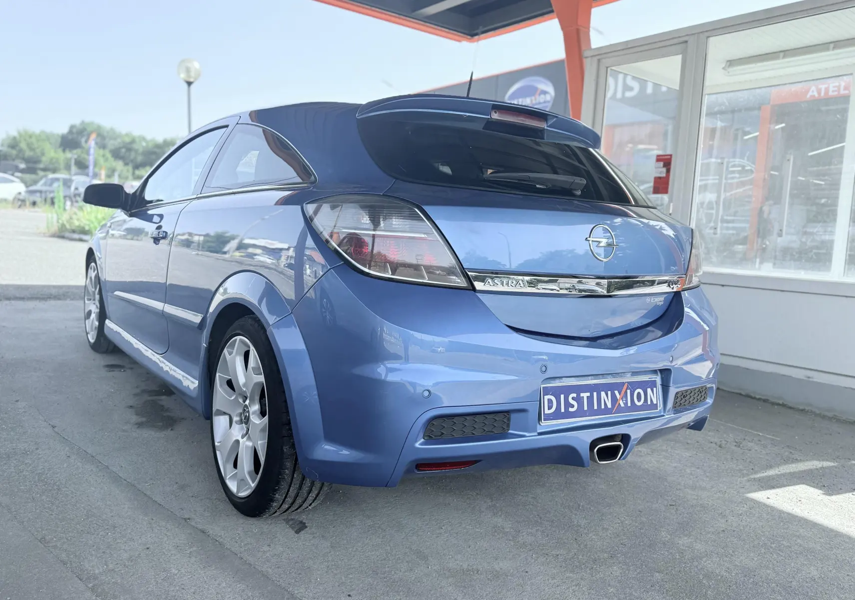 Vue 3/4 arrière droite d’une Opel Astra OPC bleue avec échappement central et jantes sport.