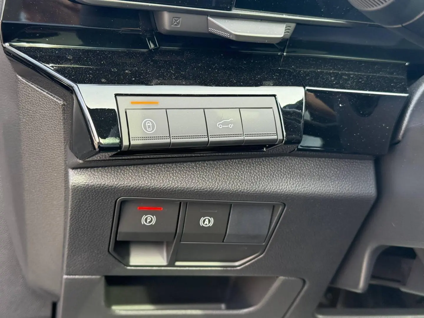 Gros plan sur les boutons de commande du tableau de bord du Renault Austral 1.2 E-Tech gris, avec éclairage LED rouge et orange.