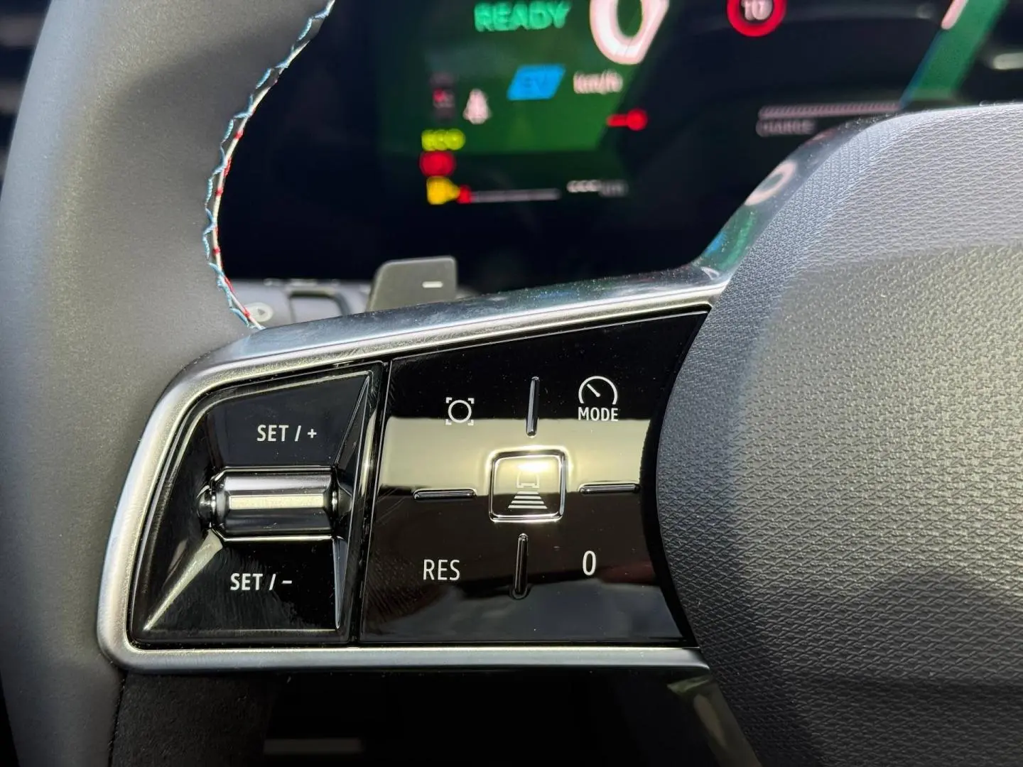 Gros plan sur les commandes du volant côté gauche du Renault Austral gris, avec affichage numérique en arrière-plan.