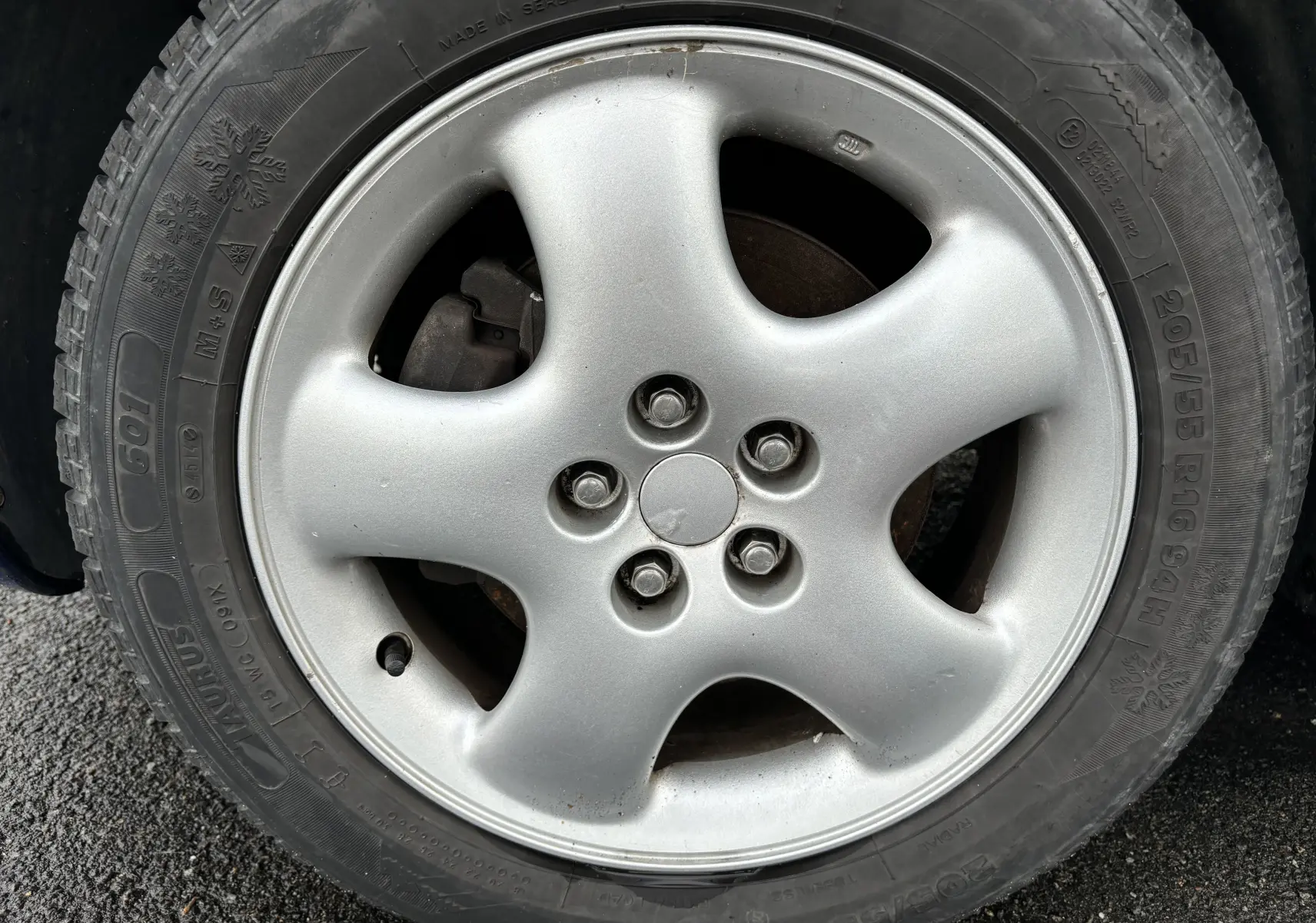 Gros plan sur la roue avant droite d'un Chrysler PT Cruiser bleu 2004, mettant en valeur le pneu hiver marqué 205/55 R16.