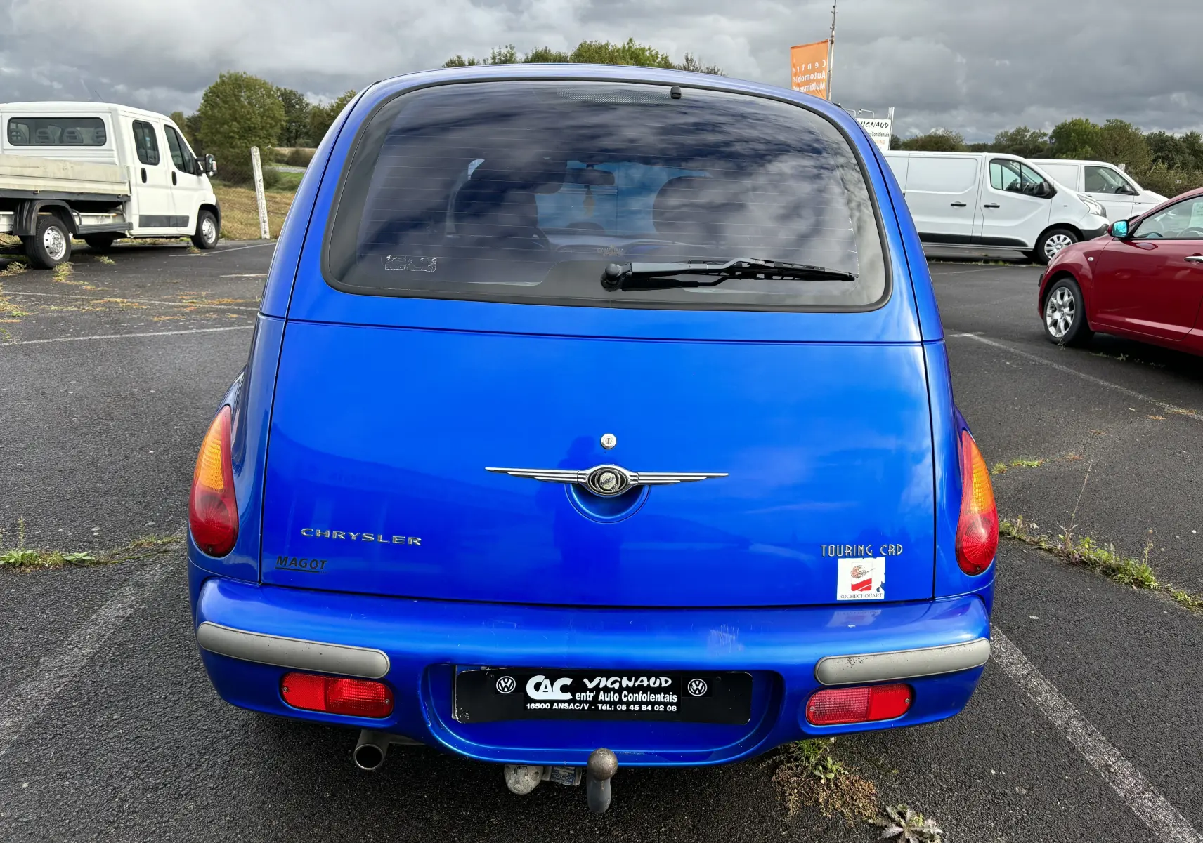 Vue arrière d'une Chrysler PT Cruiser bleue de 2004 avec logo et plaque d'immatriculation sur un parking extérieur.
