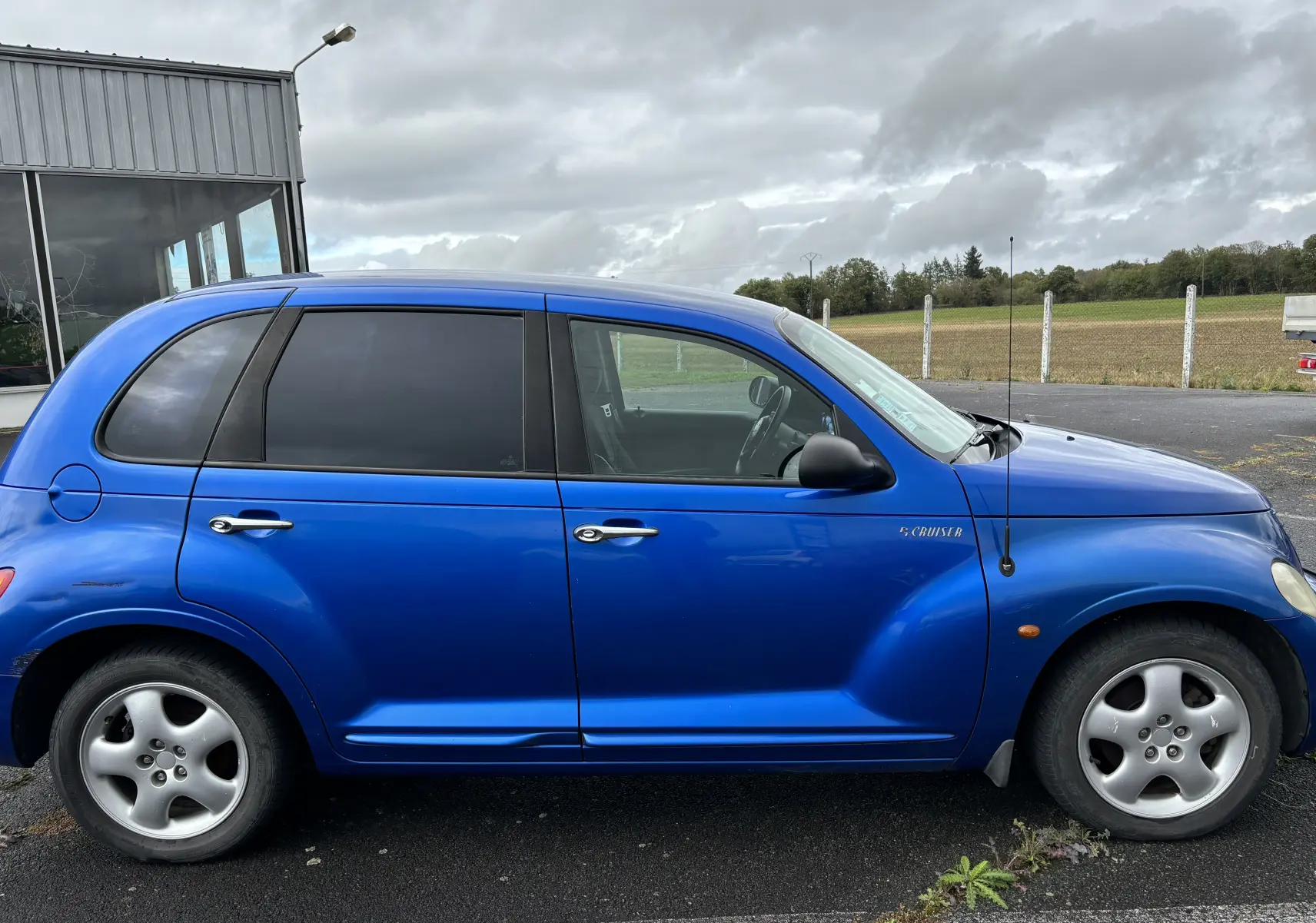 Vue de profil côté gauche d'une Chrysler PT Cruiser bleu 2004 avec vitres teintées et rétroviseur noir.