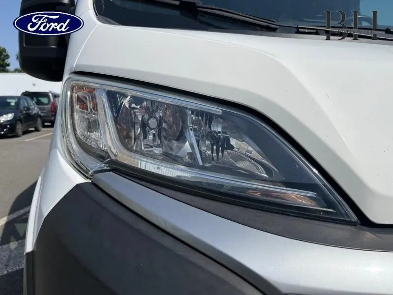 Gros plan sur le phare avant droit du Citroën Jumper FGN blanc Banquise, soulignant ses détails lumineux et contours.