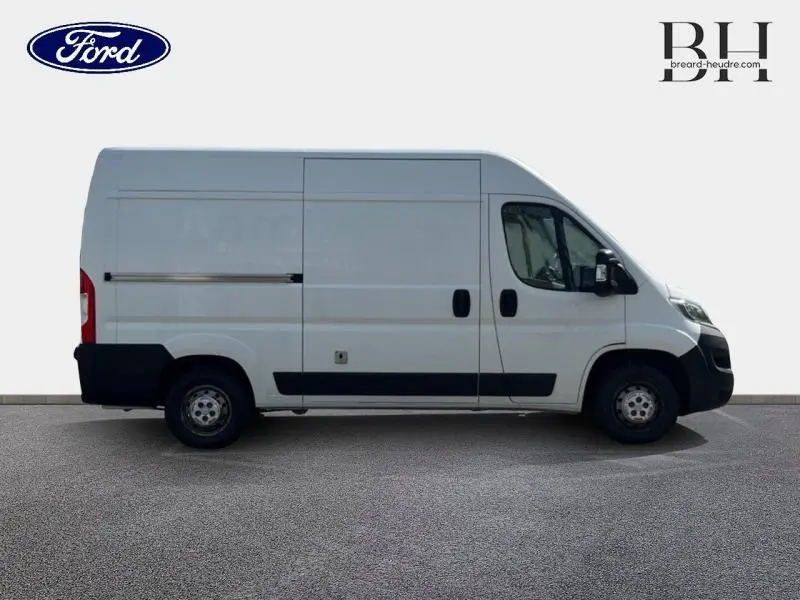 Vue latérale droite d'un utilitaire blanc Citroën Jumper FGN 33 L2H2 avec porte latérale coulissante et pare-chocs noirs.