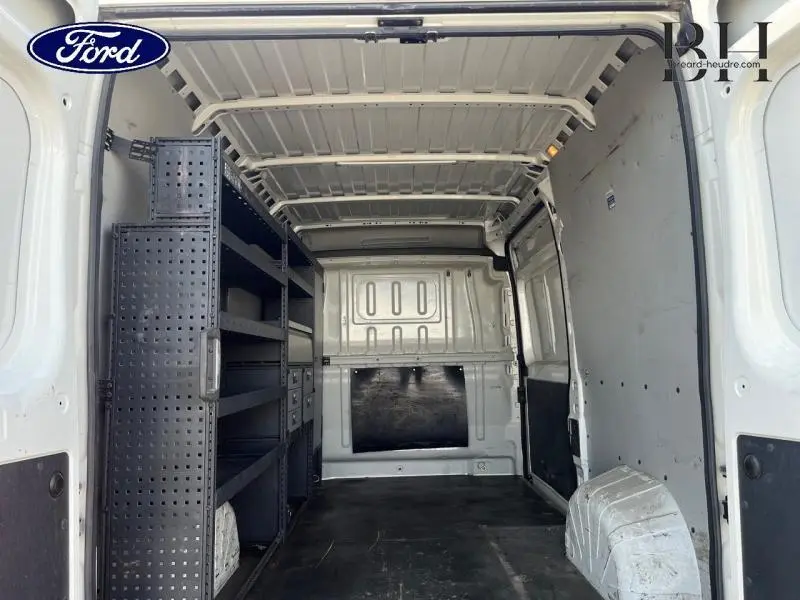 Vue intérieure arrière d’un fourgon blanc Banquise avec étagères métalliques noires à gauche et espace de chargement vide.