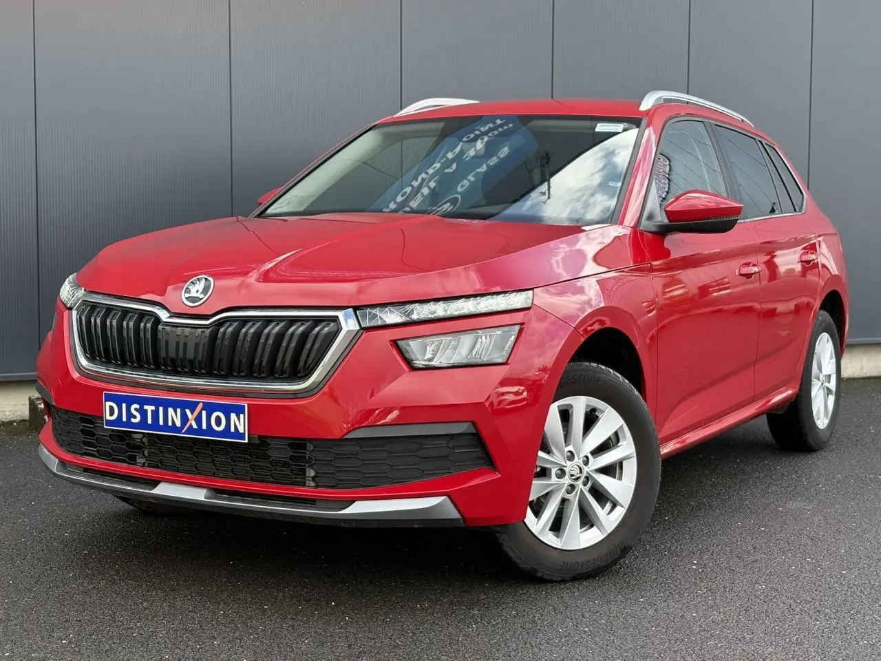 Vue 3/4 avant droite d'un Skoda Kamiq rouge Velvet avec calandre chromée et jantes alliage 16 pouces.