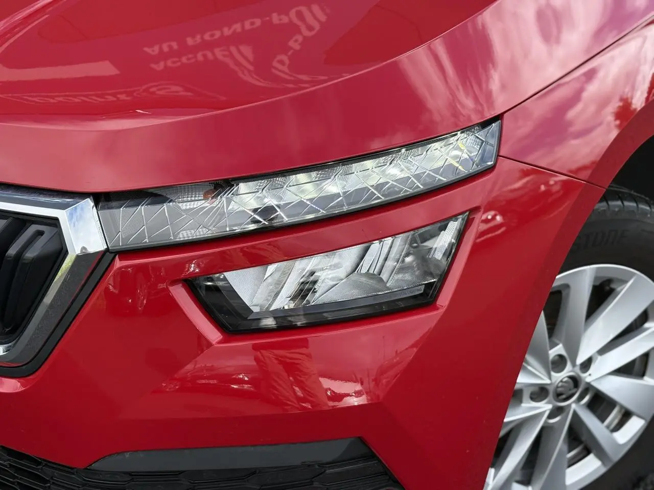 Gros plan sur le phare avant droit et la calandre d'un Skoda Kamiq Rouge Velvet 2024 avec jante alliage.