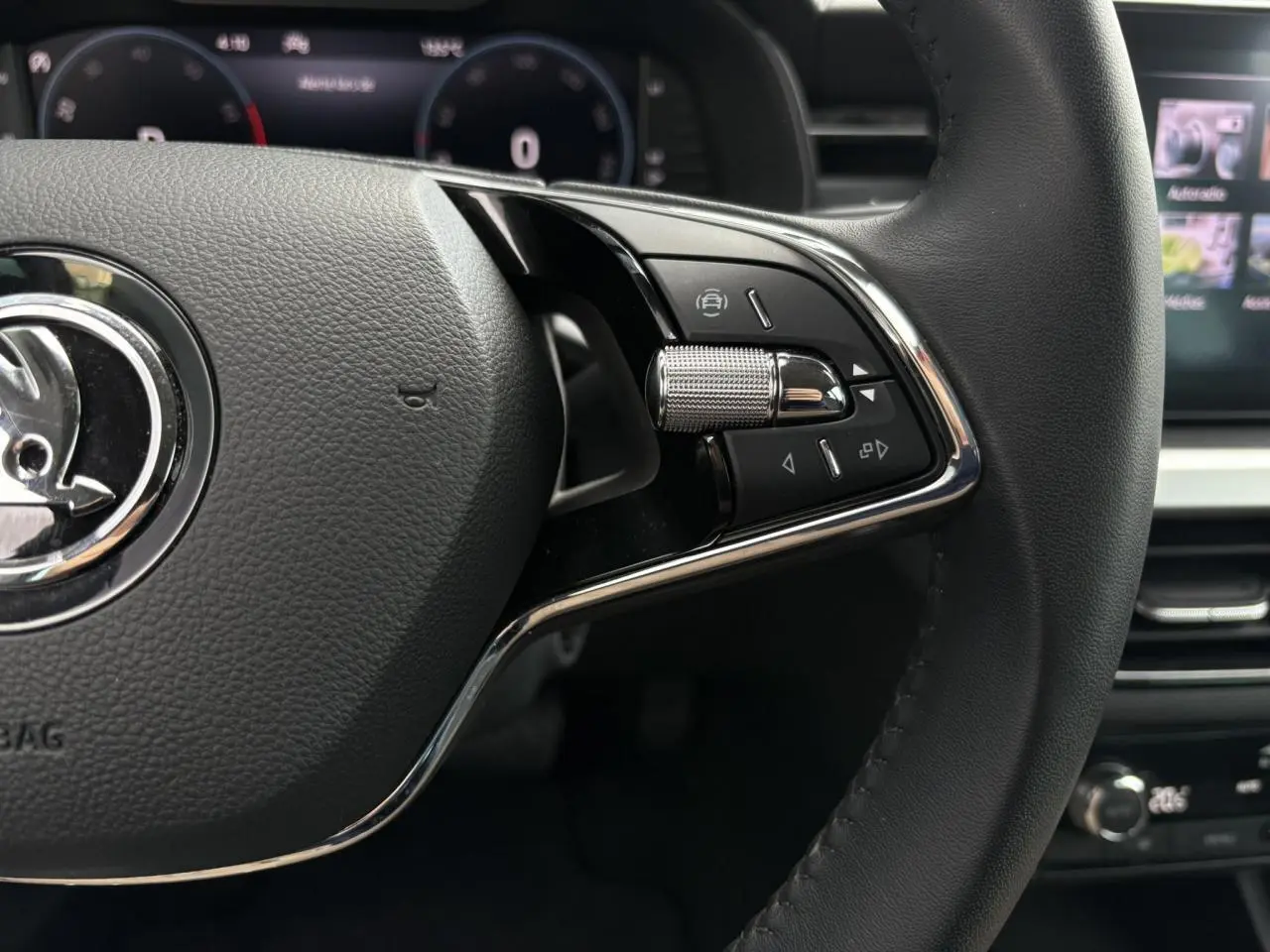 Gros plan sur le volant cuir noir multifonctions côté droit du Skoda Kamiq 2024 avec commandes intégrées et tableau de bord numérique.