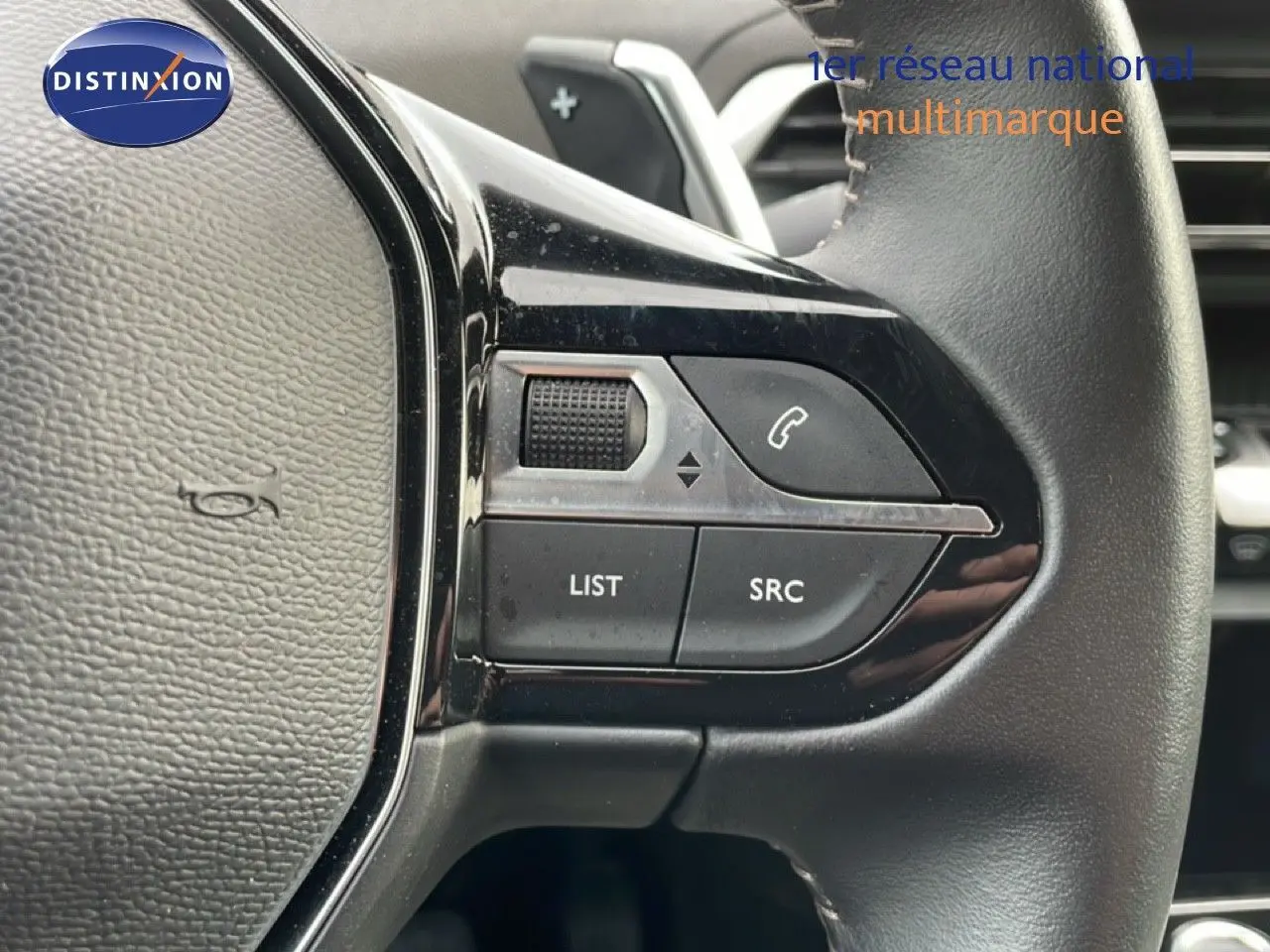 Gros plan sur les commandes gauche du volant cuir noir du Peugeot 3008 1.6 Hybrid 2024, boutons LIST et SRC visibles.