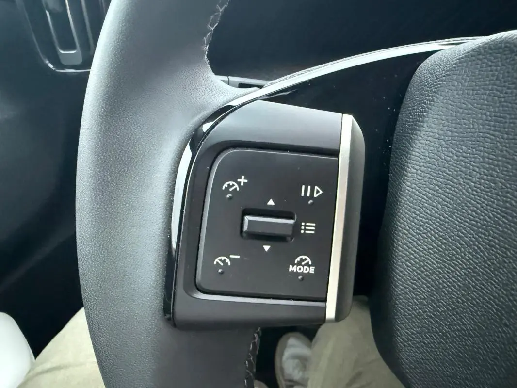 Gros plan sur les commandes de régulateur de vitesse au volant noir d'une Citroën C3 gris 2025.