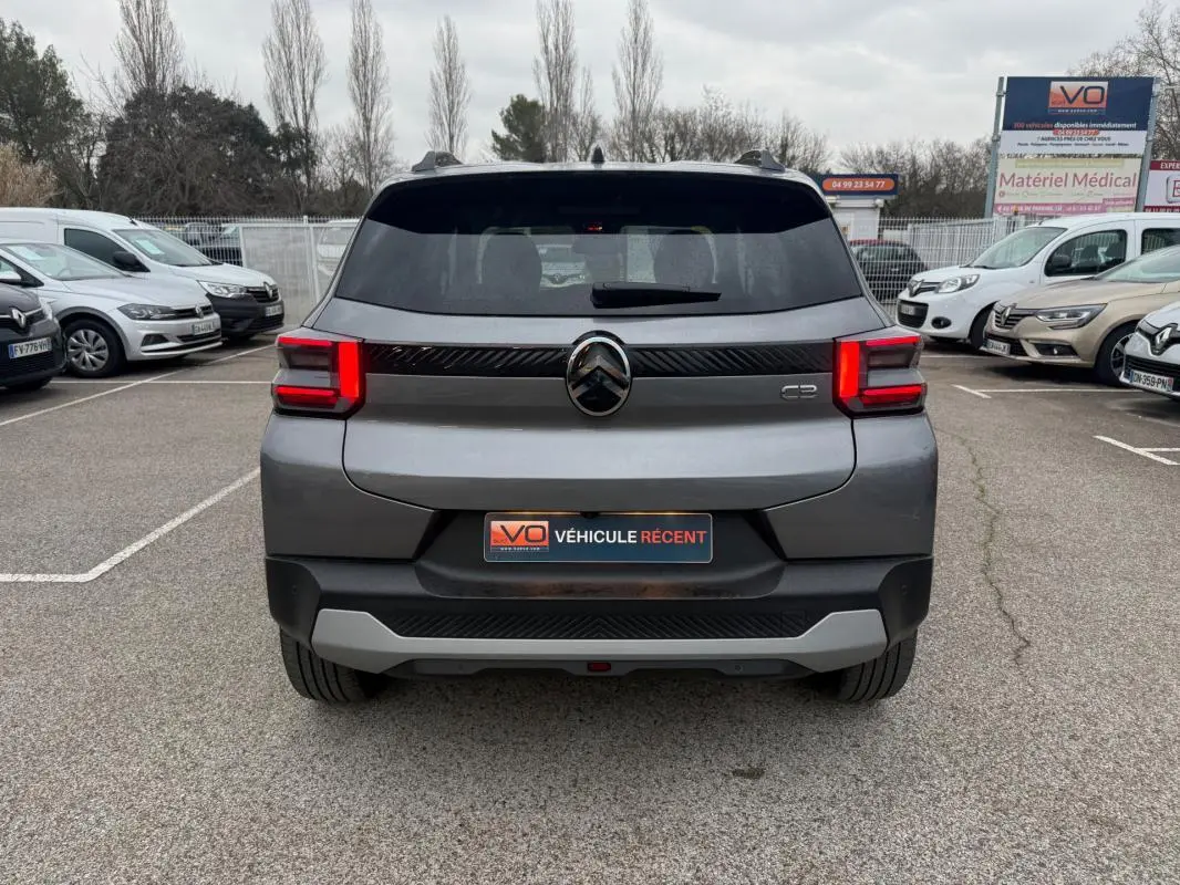Vue arrière d'une Citroën C3 gris 2025 avec feux LED distinctifs et barres de toit visibles en parking.