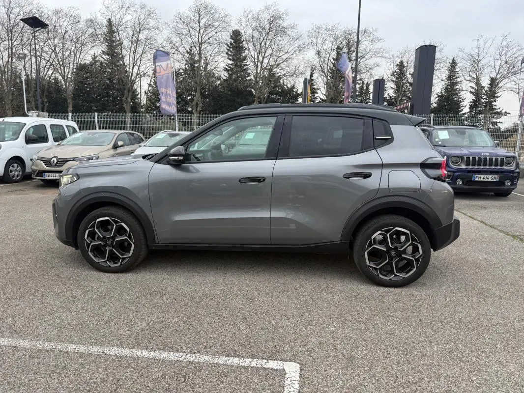 Vue de profil côté gauche d'une Citroën C3 gris 2025 avec jantes alliage 17 pouces et barres de toit noires.