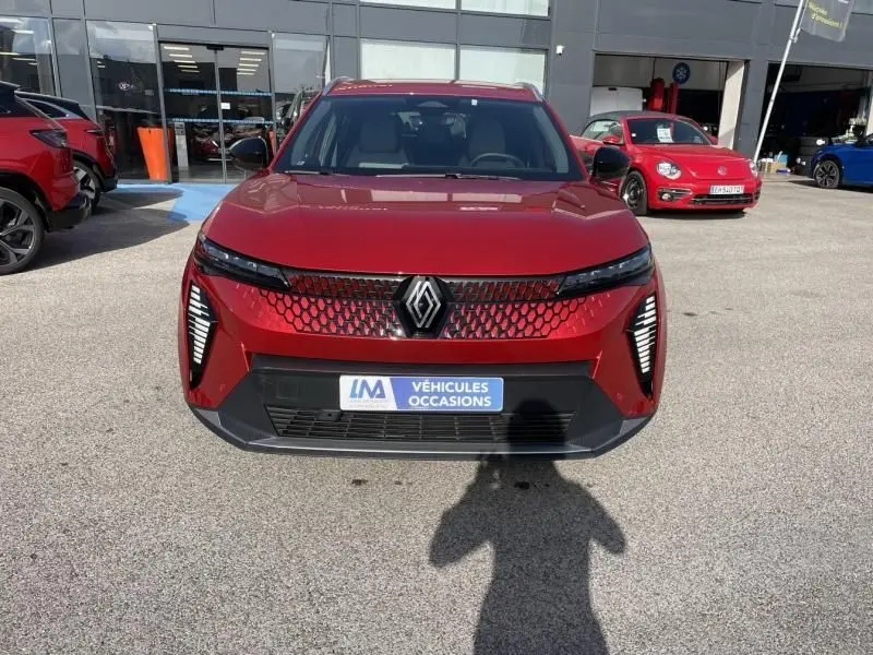 Vue de face du Renault Scénic E-Tech électrique rouge flamme 2024, avec calandre à motif hexagonal et feux LED verticaux.