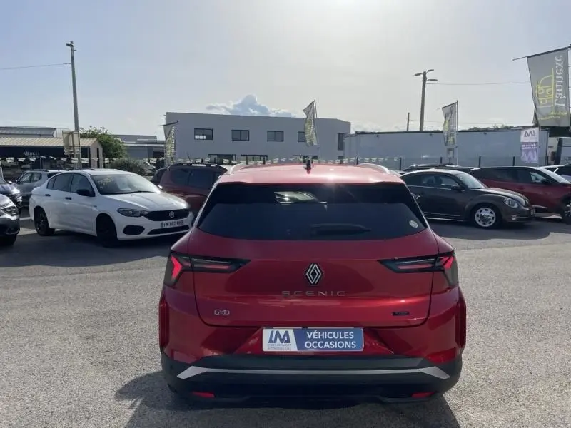Vue arrière d’un Renault Scénic E-Tech électrique rouge flamme 2024, avec feux arrière LED et logo central bien visibles.