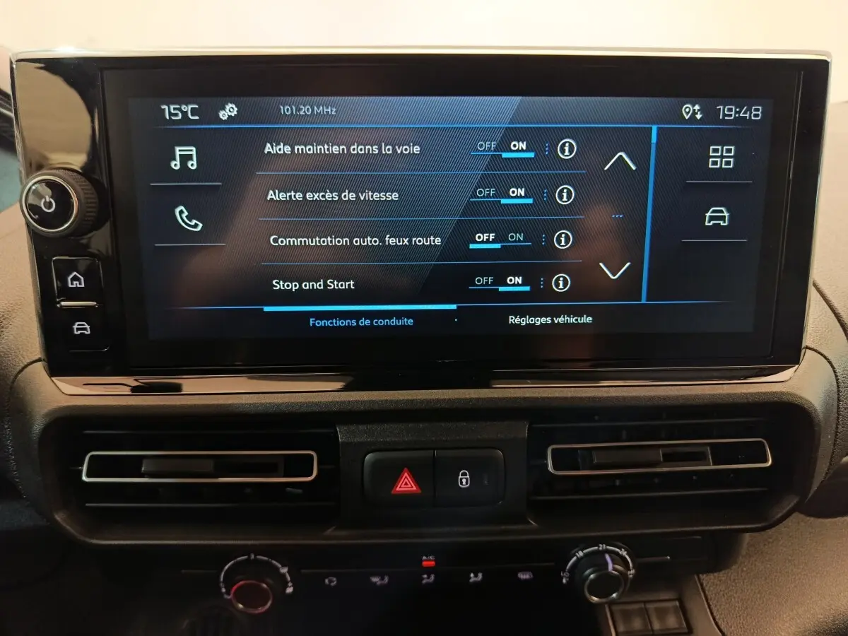 Écran tactile central du Peugeot Partner 2025 affichant les réglages d’aides à la conduite, avec commandes et aérateurs en dessous.