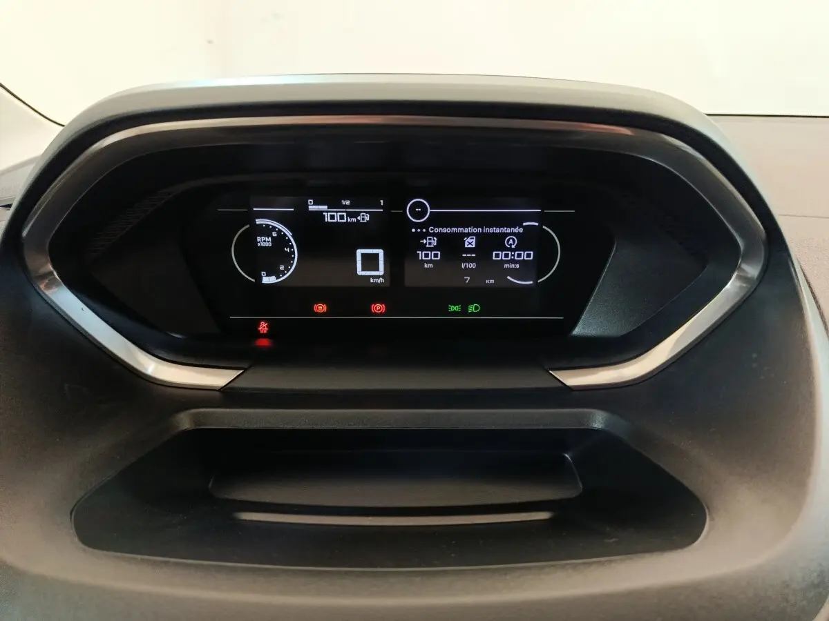 Vue rapprochée du tableau de bord numérique du Peugeot Partner 2025, affichant la consommation instantanée et les alertes.