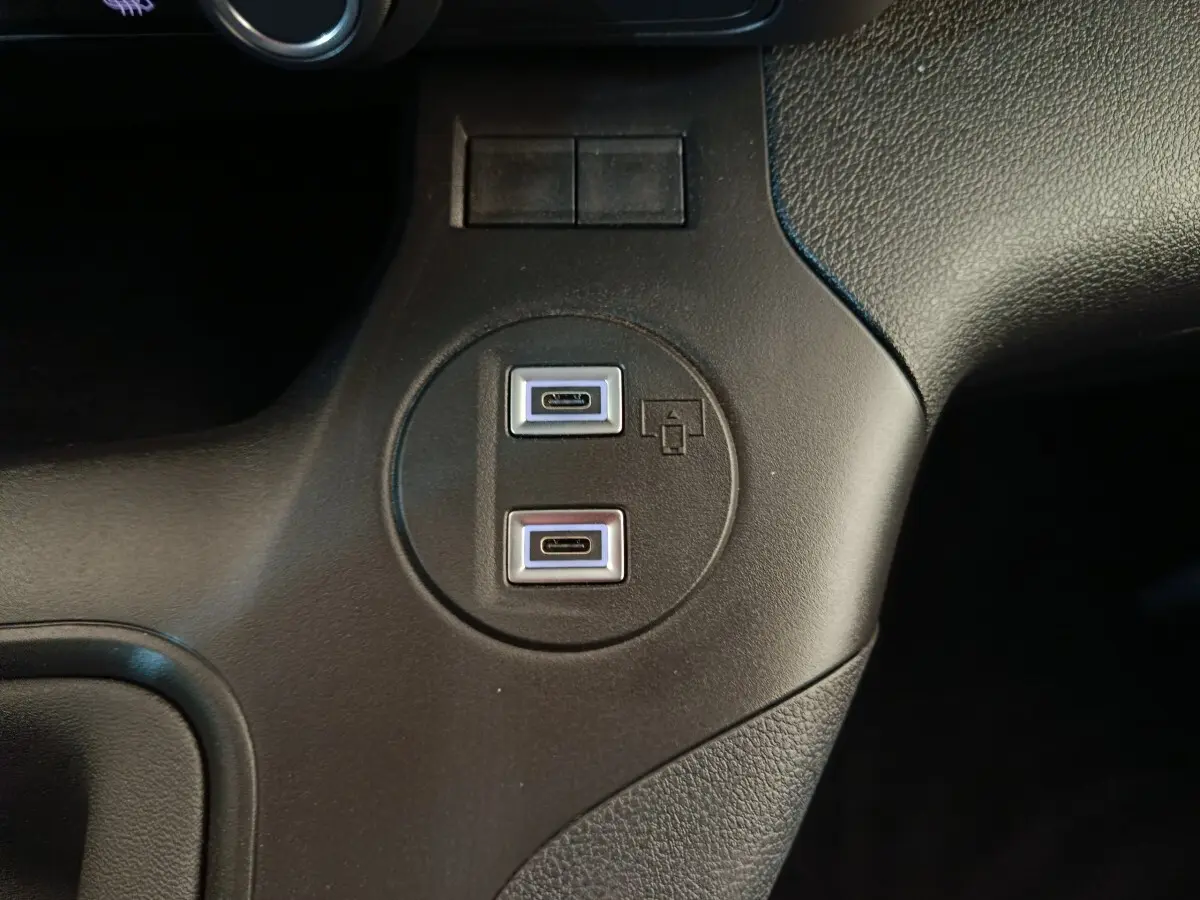 Gros plan sur deux ports USB-C intégrés dans la console centrale noire du Peugeot Partner blanc 2025.