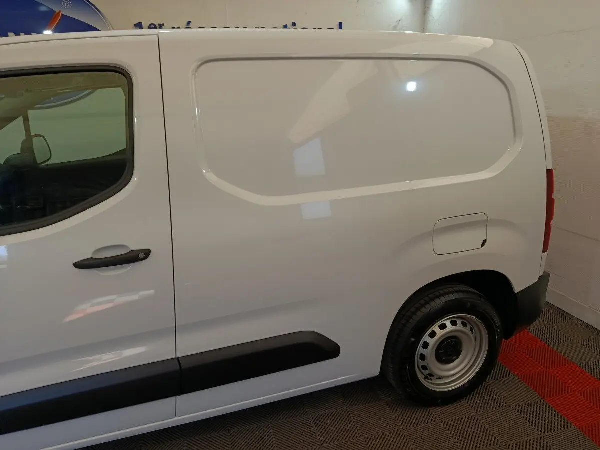 Vue latérale droite d'un utilitaire Peugeot Partner blanc, version Taille M, avec porte latérale pleine et jante acier simple.
