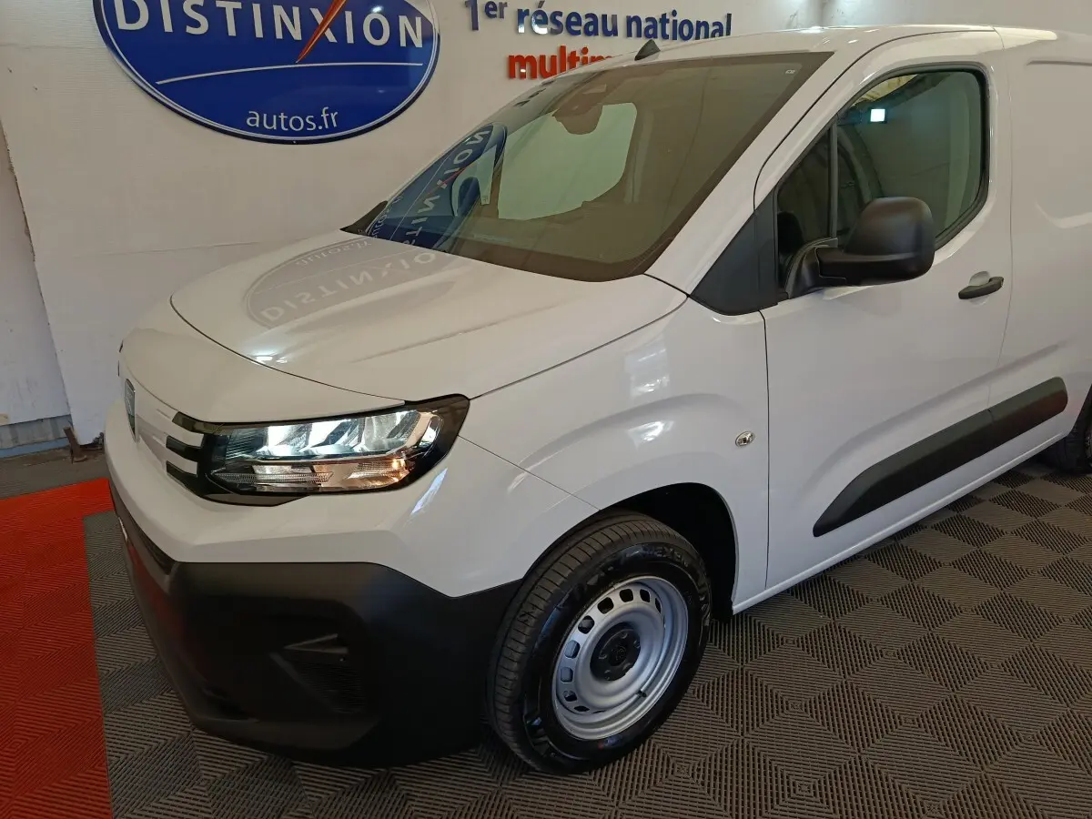 Vue 3/4 avant droit du Peugeot Partner blanc 2025 avec pare-chocs noir et jante acier simple.