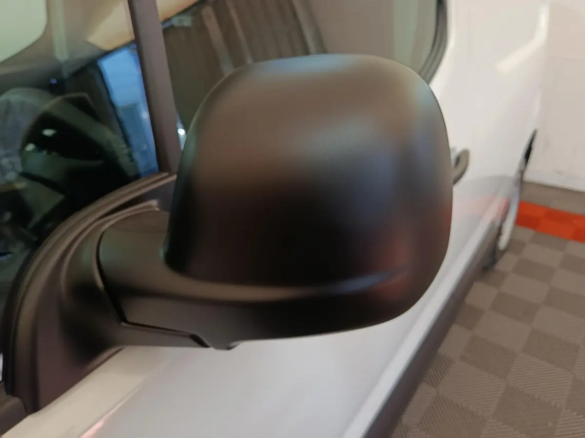 Rétroviseur noir en gros plan côté gauche du Peugeot Partner blanc, vue rapprochée sur porte avant.