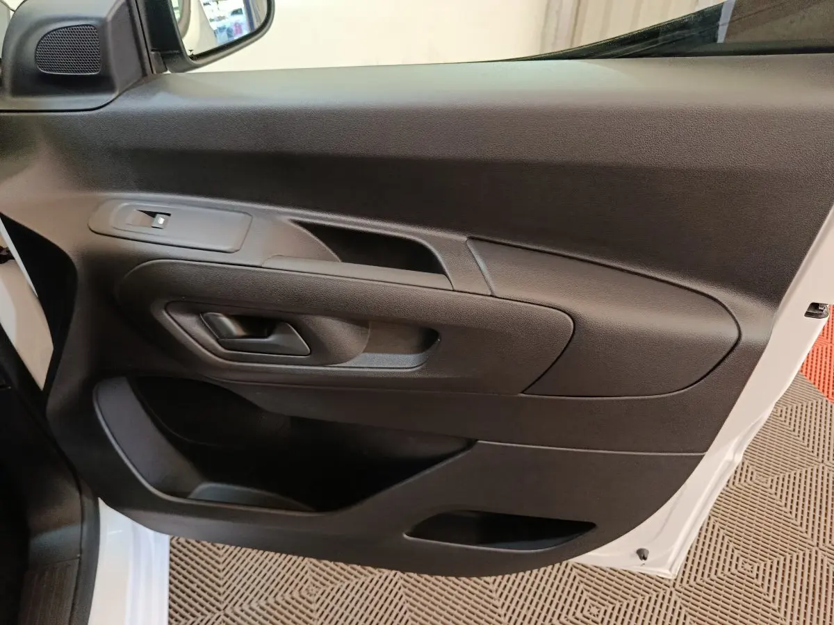 Vue rapprochée de la porte côté conducteur noire du Peugeot Partner blanc, avec poignée et commande de vitre.