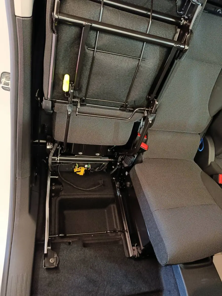 Vue intérieure en plongée du siège passager avant relevé du Peugeot Partner blanc, montrant la structure métallique et le rangement sous siège.