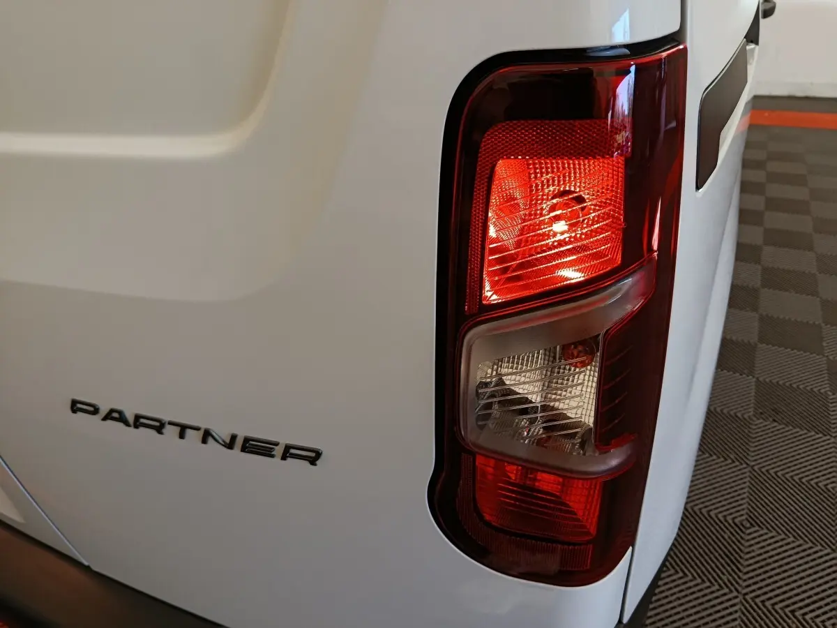 Gros plan sur le feu arrière droit et le logo PARTNER du utilitaire Peugeot blanc, vue arrière droite.