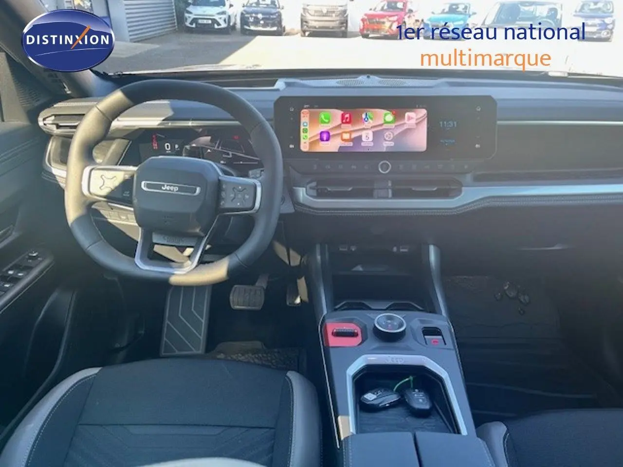 Vue intérieure avant du Jeep Compass 2026, tableau de bord et volant noirs avec écran tactile central allumé.