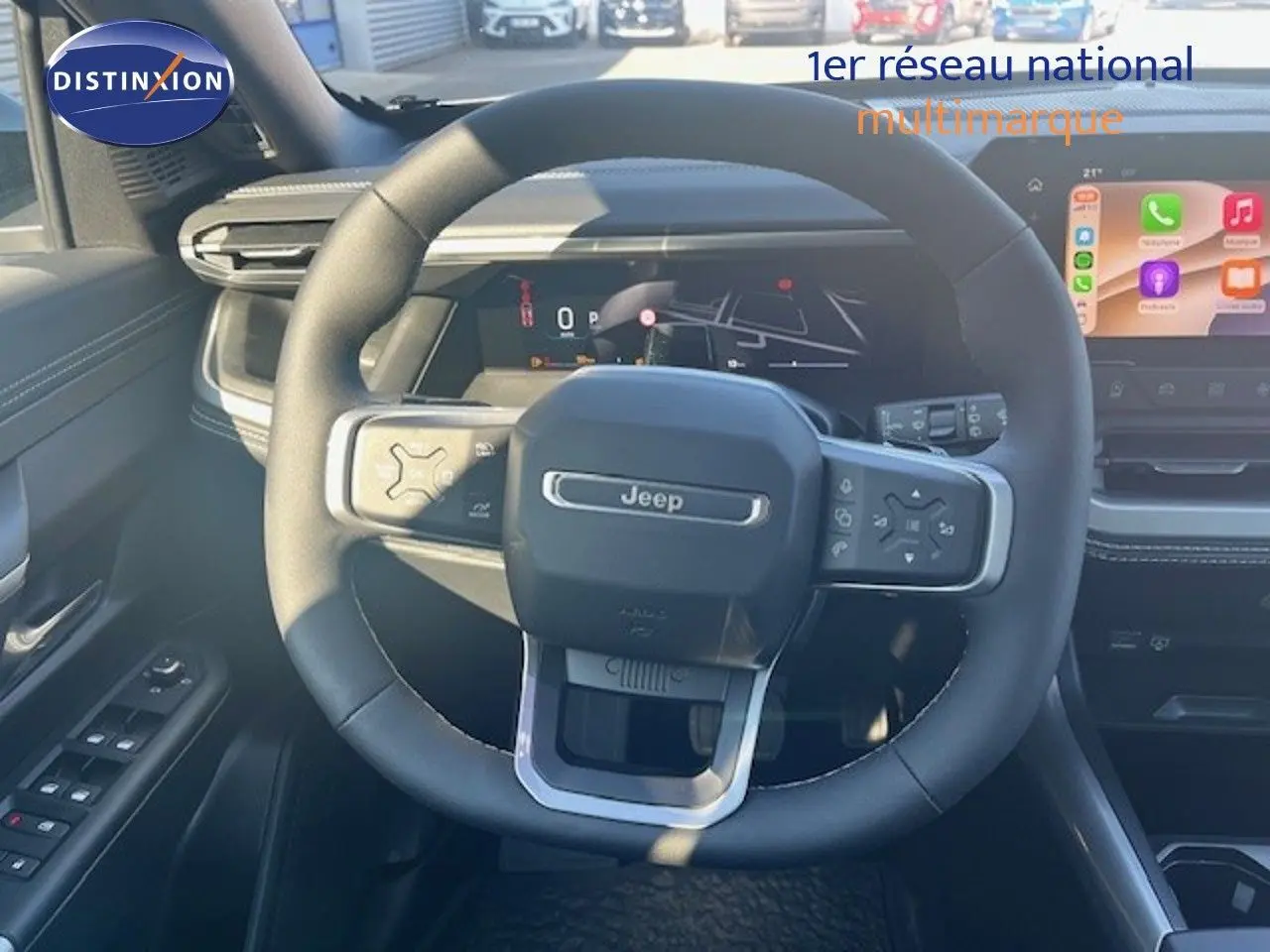 Vue centrée sur le volant Jeep noir du Compass 2026, tableau de bord digital et écran tactile en arrière-plan.