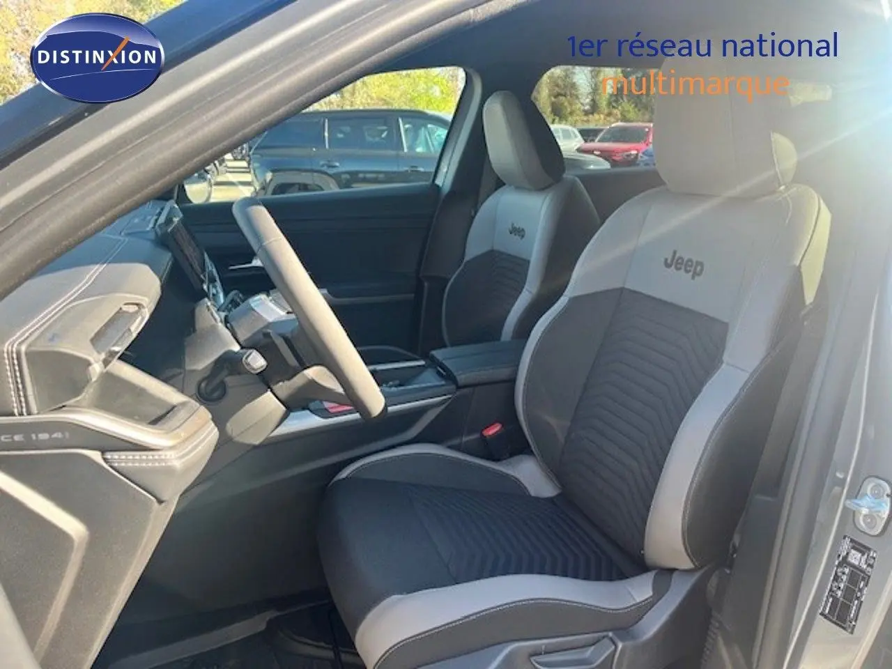 Vue intérieure côté conducteur du Jeep Compass 2026, sièges bi-ton gris clair et noir avec logo Jeep brodé.
