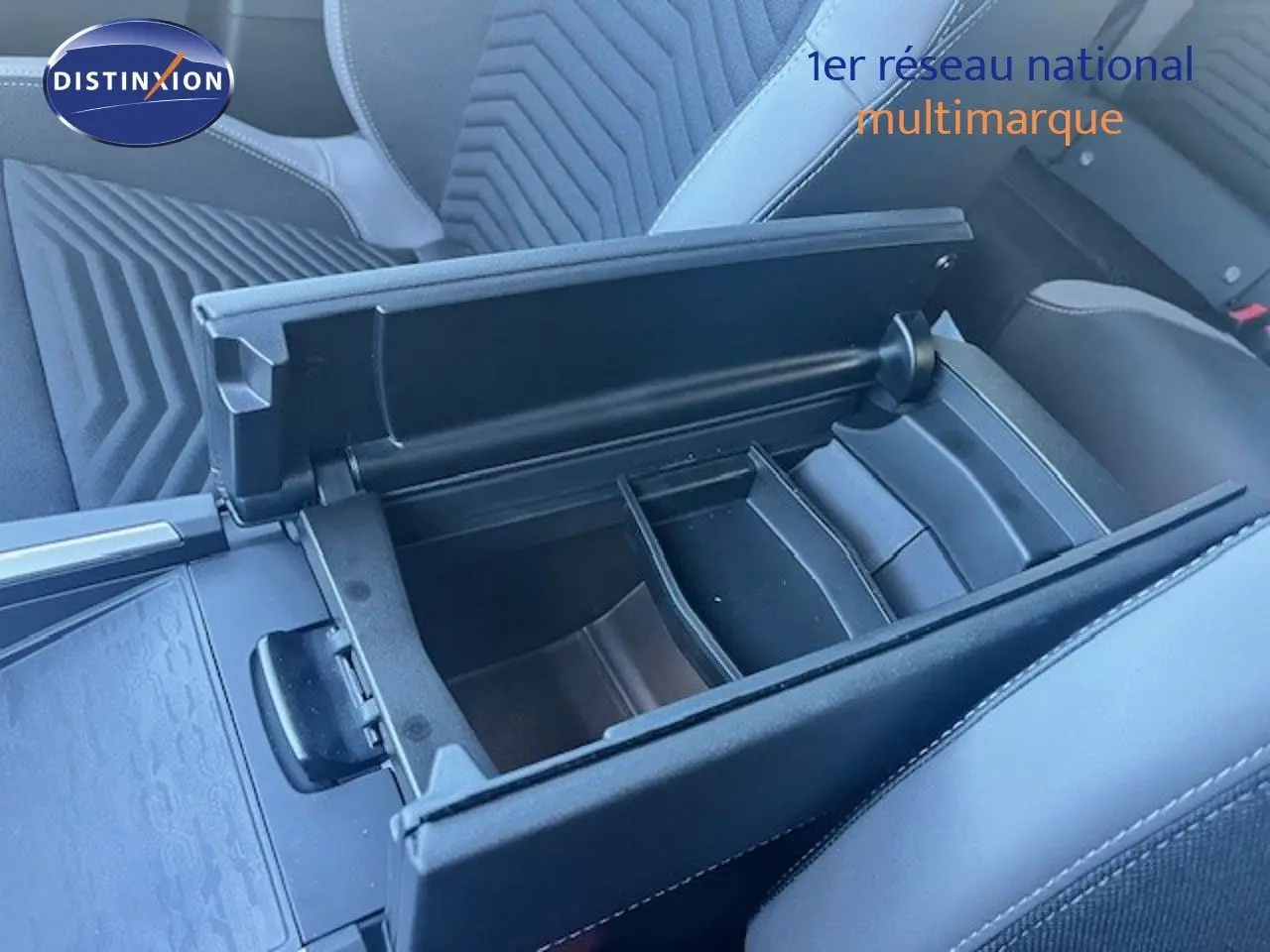 Vue rapprochée de l'accoudoir central ouvert et des sièges en tissu gris à motifs géométriques dans un Jeep Compass 2026.