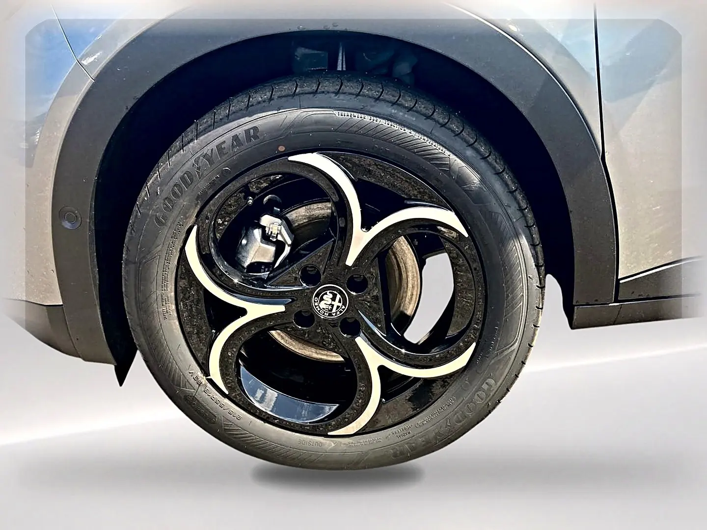 Gros plan sur la roue avant droite grise d’une Alfa Romeo Junior 1.2 hybride avec jante en alliage noir et argent.