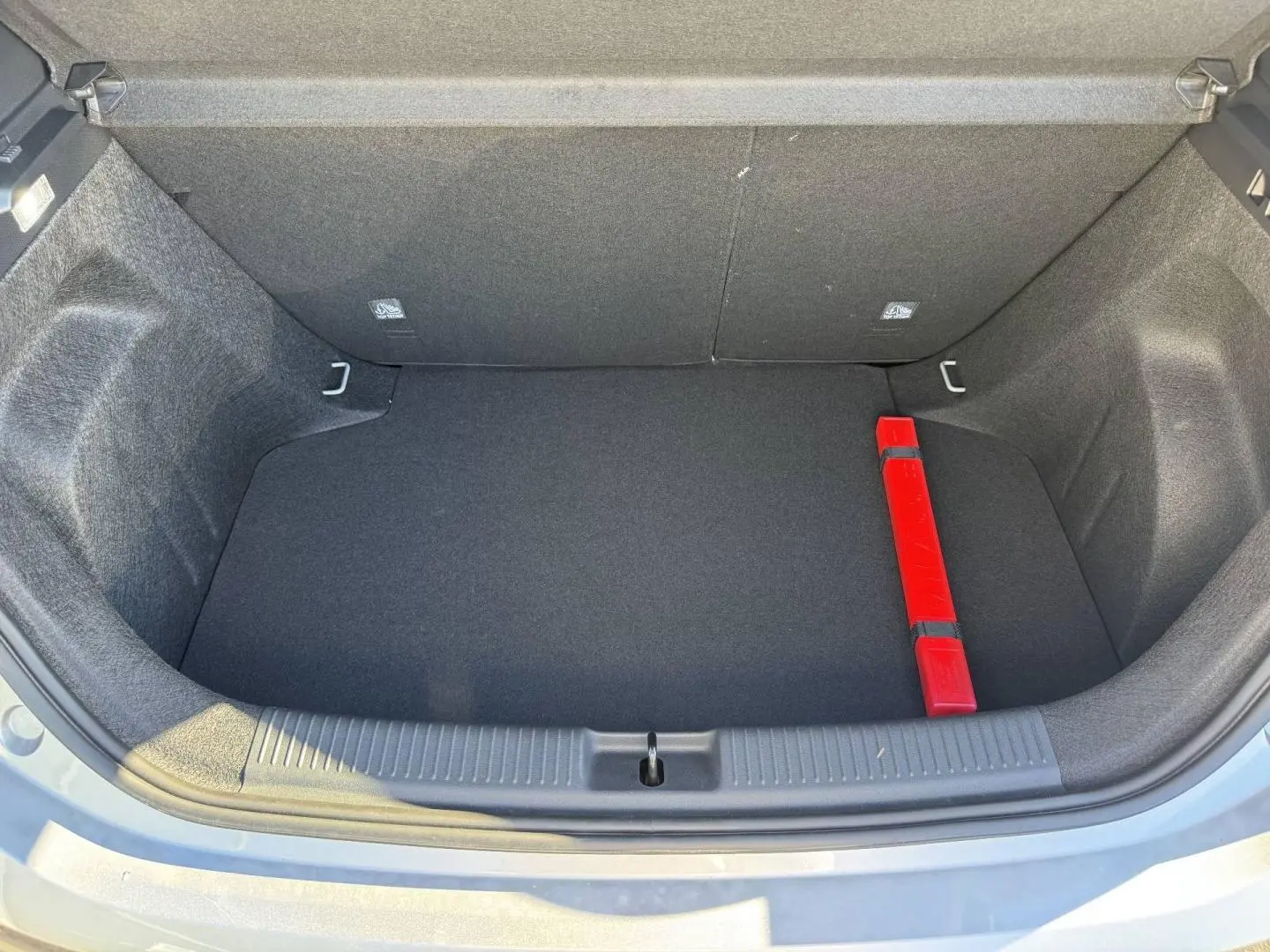 Coffre ouvert vu de dessus d'une MG3 Cosmic Silver, avec tapis noir et triangle de signalisation rouge.