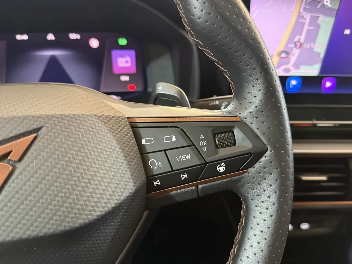 Gros plan sur le volant en cuir perforé noir du CUPRA Formentor 2023 avec commandes multifonctions et tableau de bord numérique.