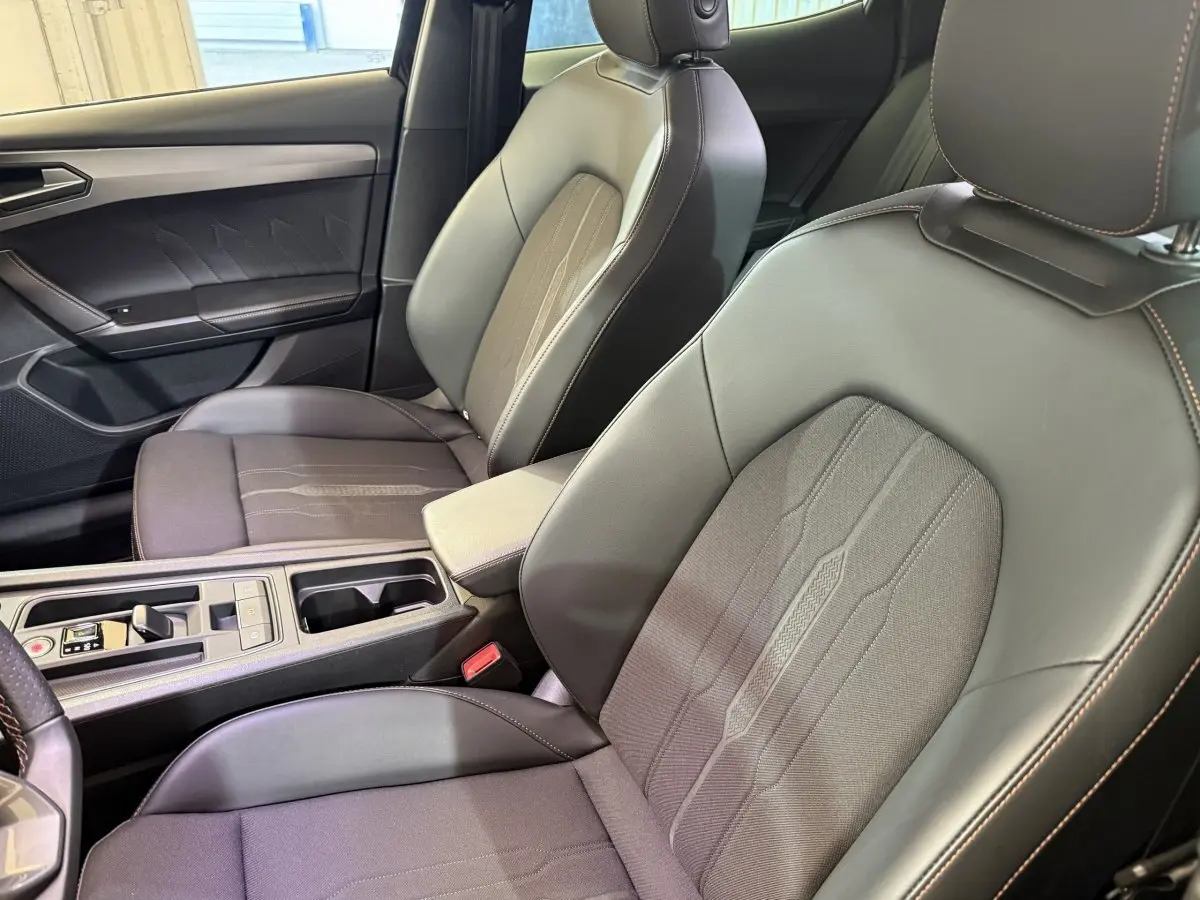 Gros plan sur les sièges avant en cuir et tissu gris du CUPRA Formentor avec surpiqûres orange visibles côté conducteur.