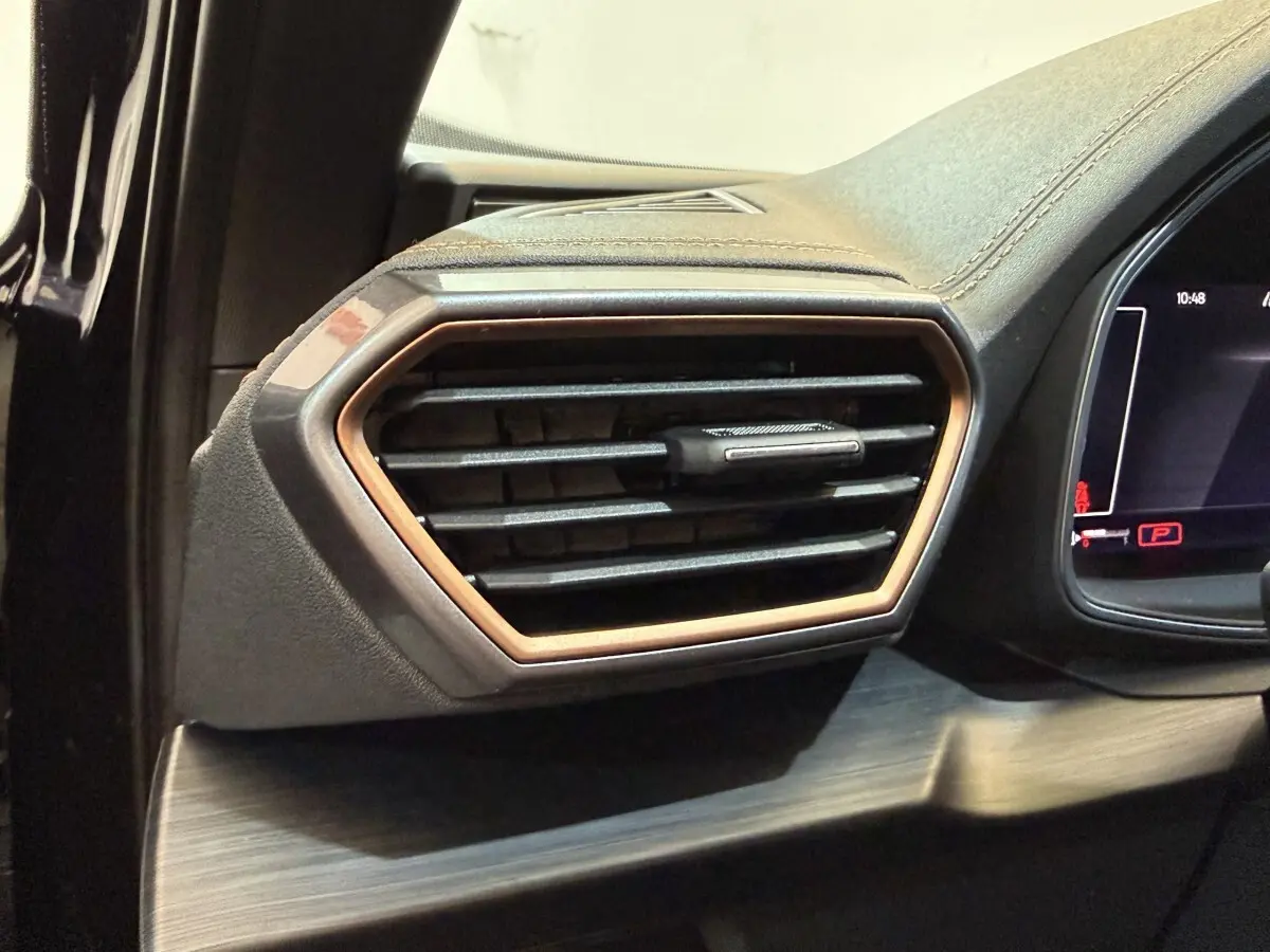 Gros plan sur la sortie d'air latérale droite du tableau de bord du CUPRA Formentor noir avec contour bronze.