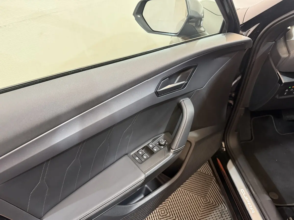 Intérieur côté conducteur noir du CUPRA Formentor 2023, avec commandes vitres et poignée de porte visible.