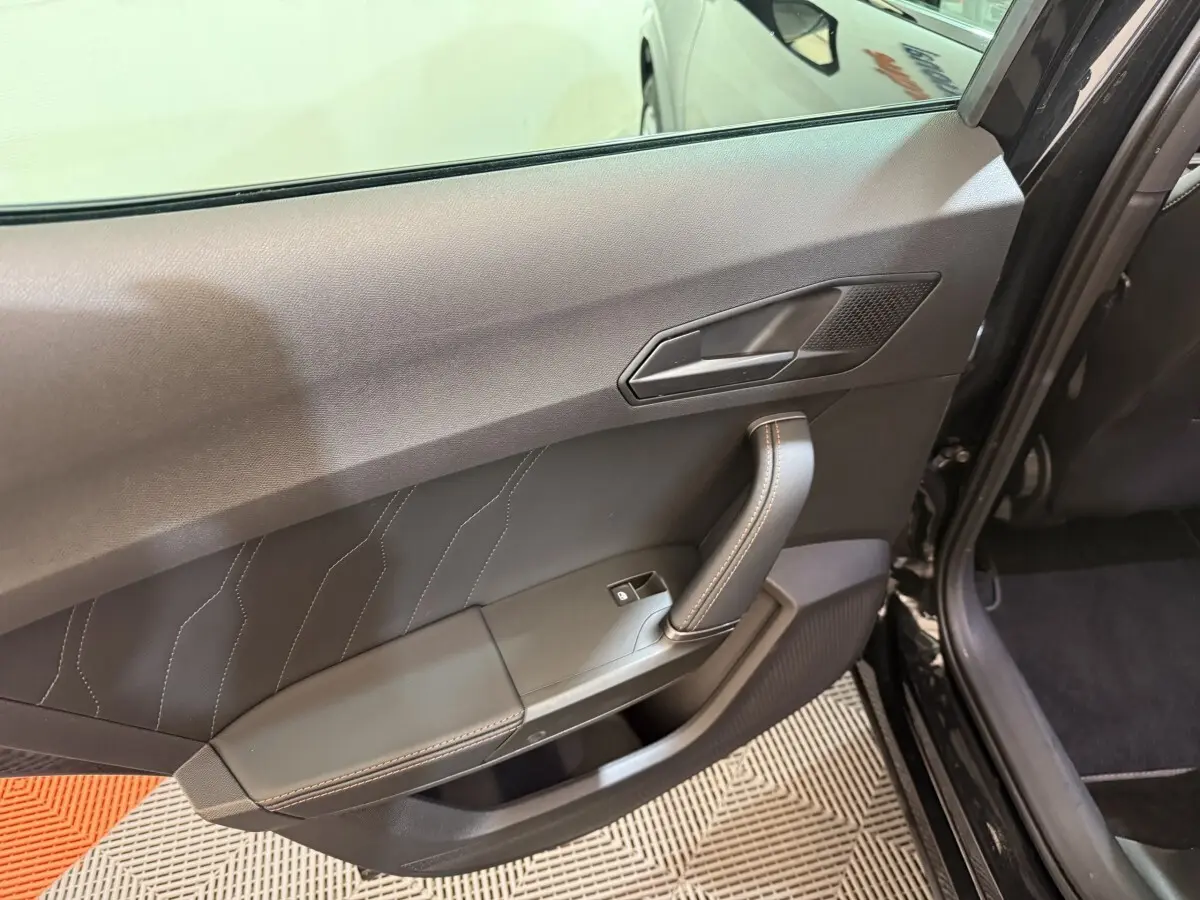 Vue intérieure de la porte arrière gauche noire du CUPRA Formentor 2023 avec poignée et bouton de vitre électrique.