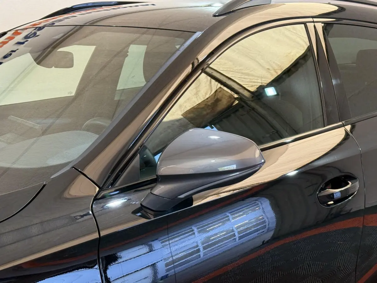 Gros plan sur le rétroviseur côté conducteur d'une CUPRA Formentor noire 2023 avec reflet lumineux sur la carrosserie.